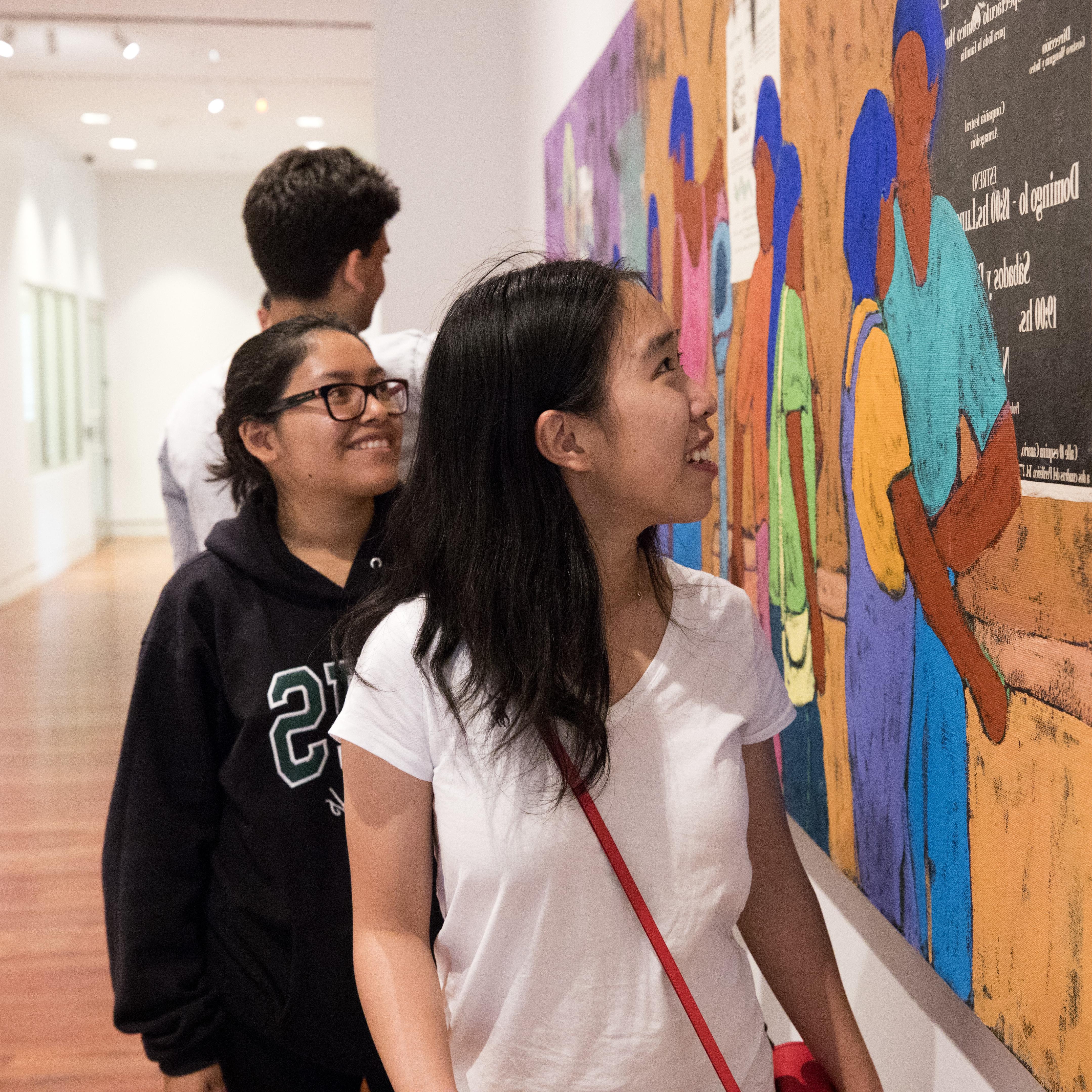 A first gen student looks at a southwestern mural at the Fine Art Center